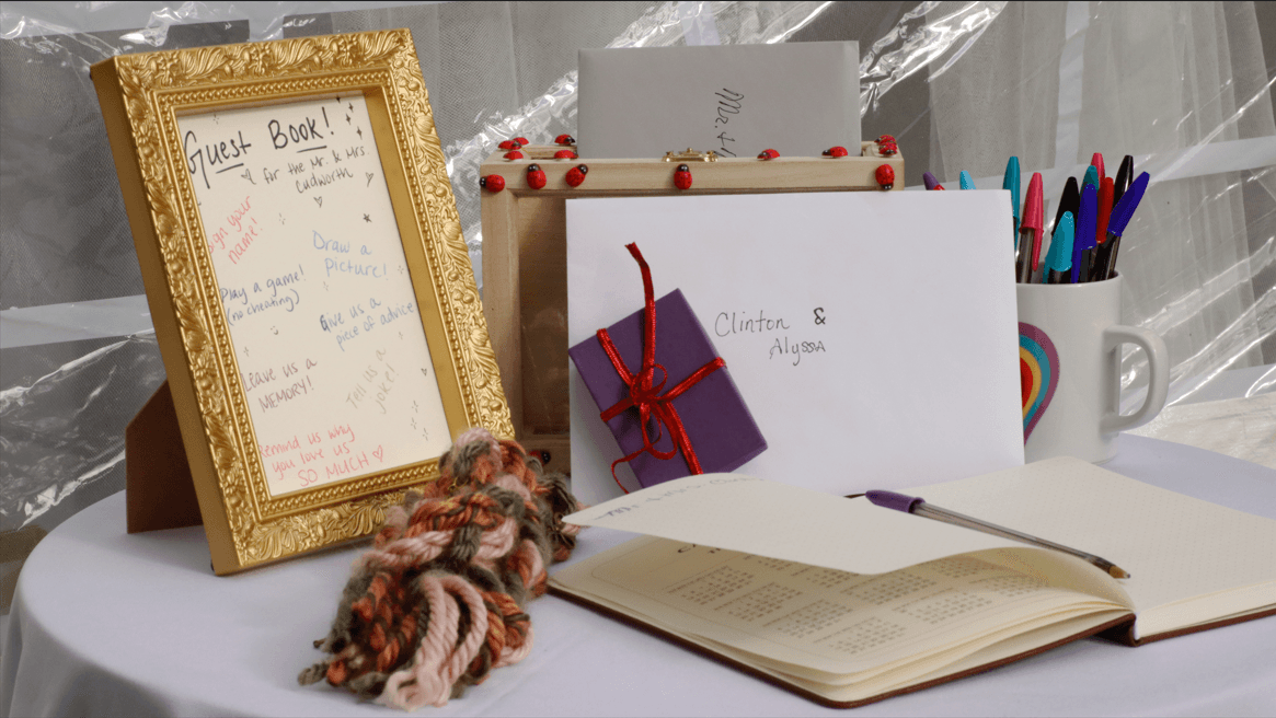 A table set up with a guest book, colorful pens, a gift envelope, and decorative yarn.
