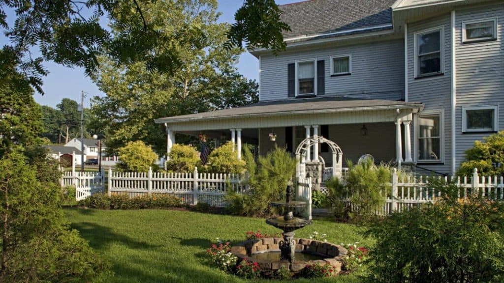 A charming house with a front porch, surrounded by a well-maintained garden and white picket fence.