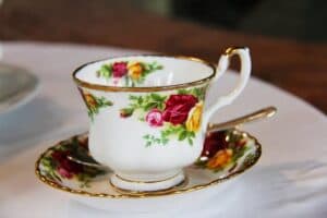 A delicate floral teacup with a matching saucer and ornate gold detailing.