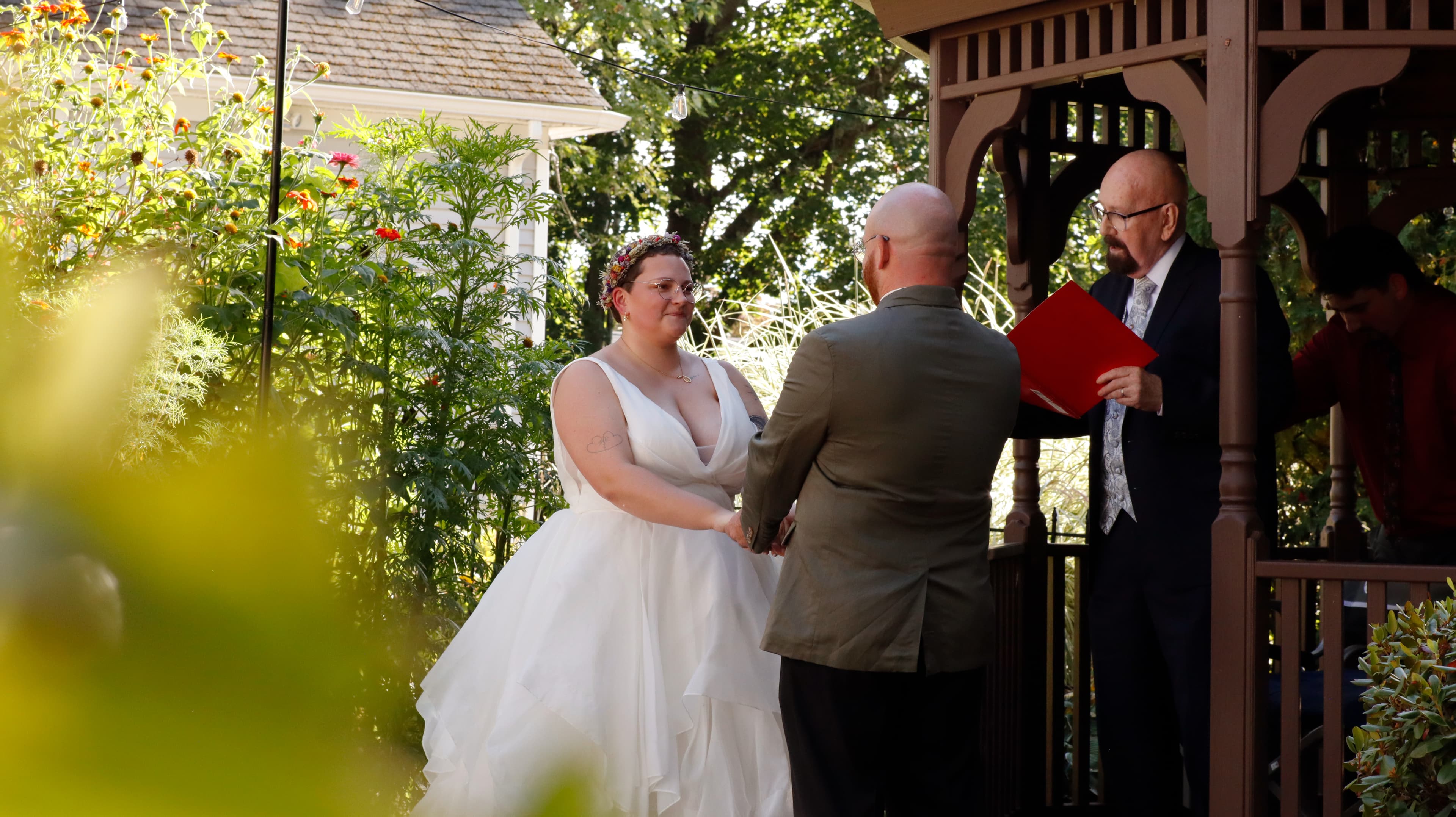 A bride and groom exchange vows under a gazebo during a wedding ceremony.