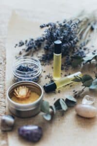 A collection of essential oils, dried lavender, and crystals arranged on a natural surface.
