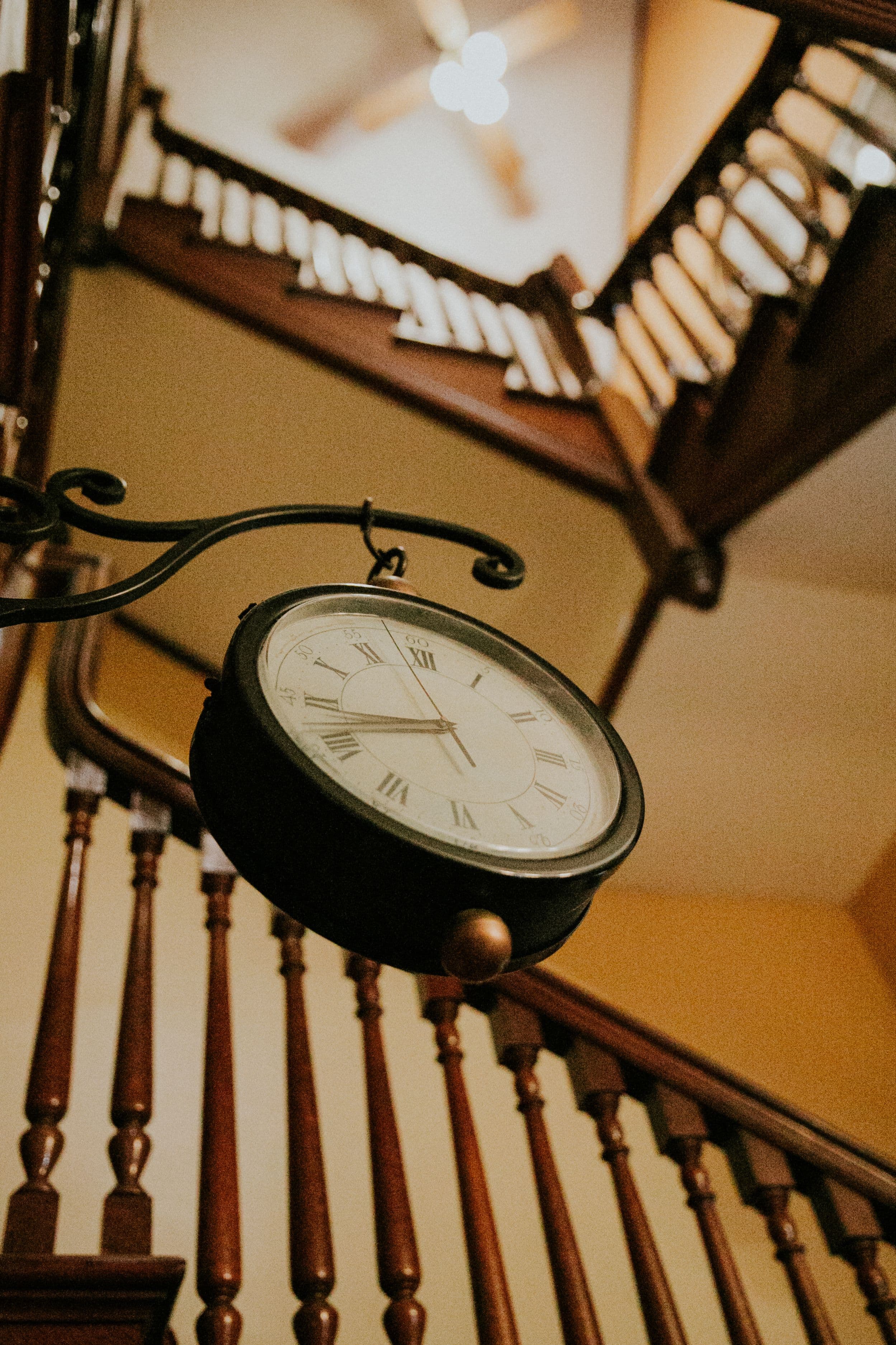 A vintage wall clock hangs above a wooden staircase.