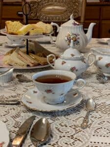 A beautifully set tea table with a cup of tea, teapot, and assorted treats.