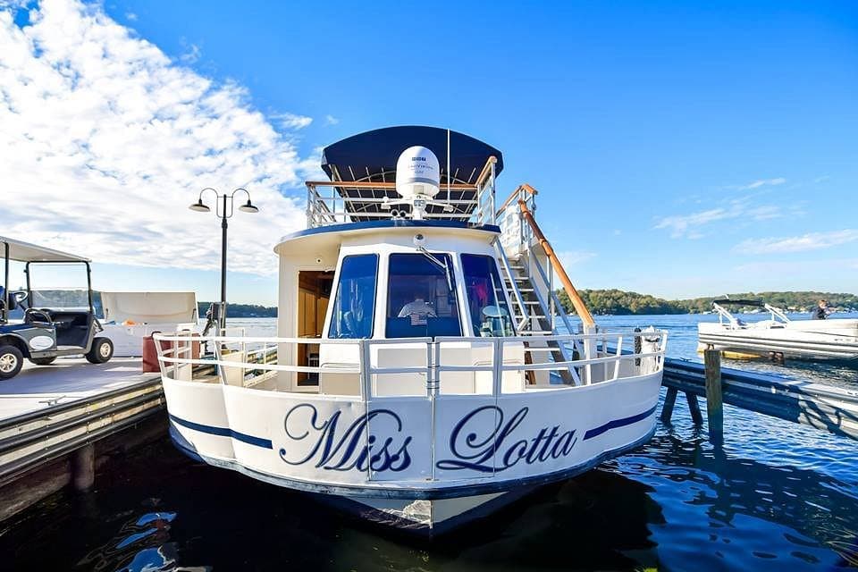 A boat named "Miss Lotta" docked at a marina under a clear blue sky.