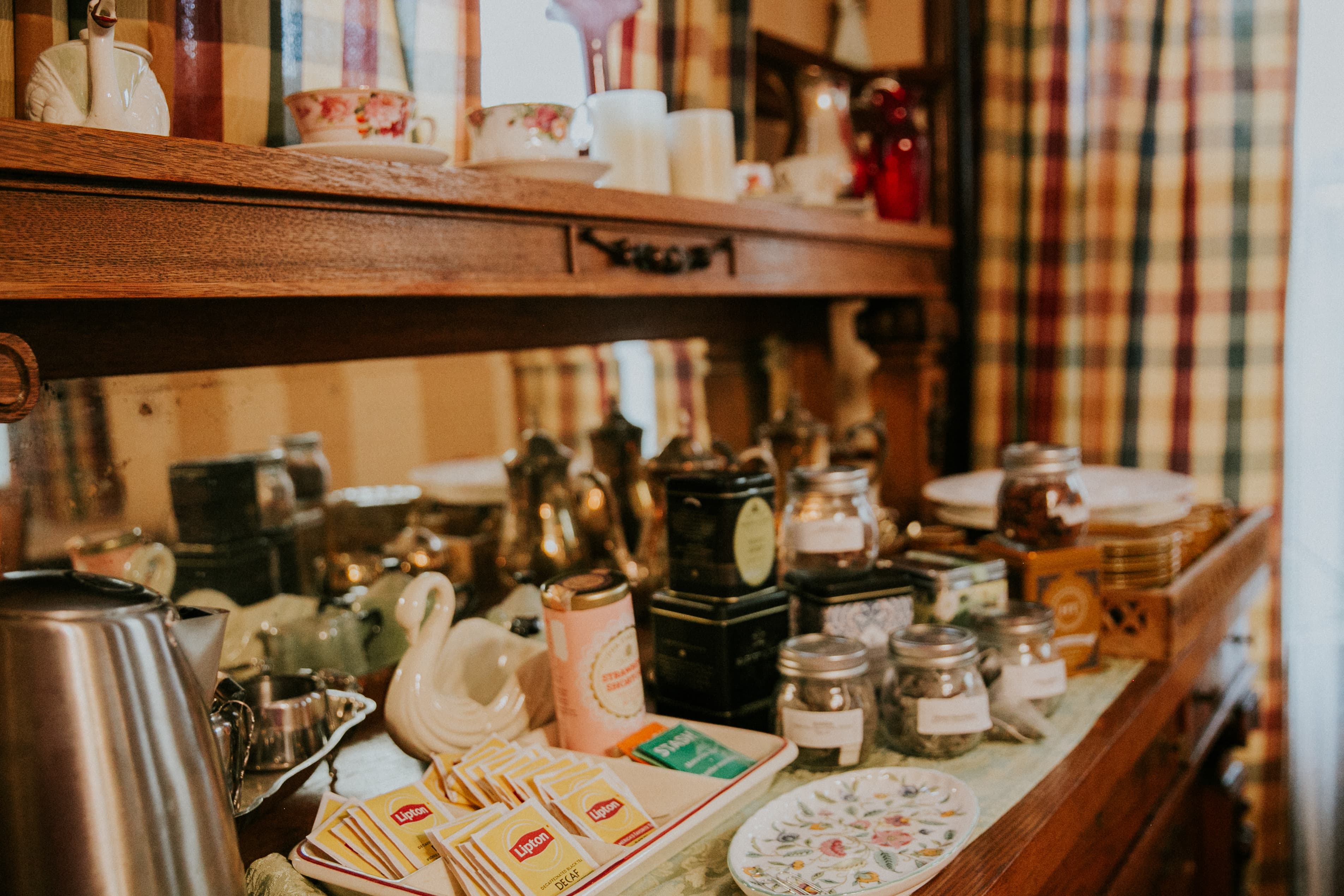 A wooden shelf filled with tea, jars, and decorative items in a cozy kitchen setting.