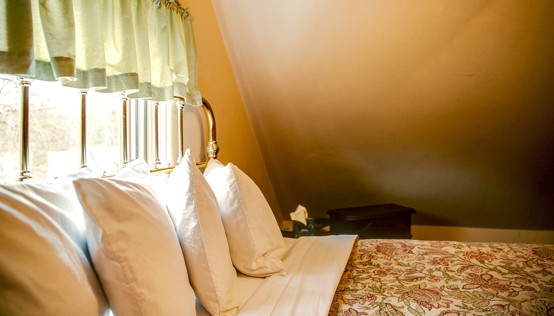 Cozy bedroom corner with decorative pillows and a floral bedspread.