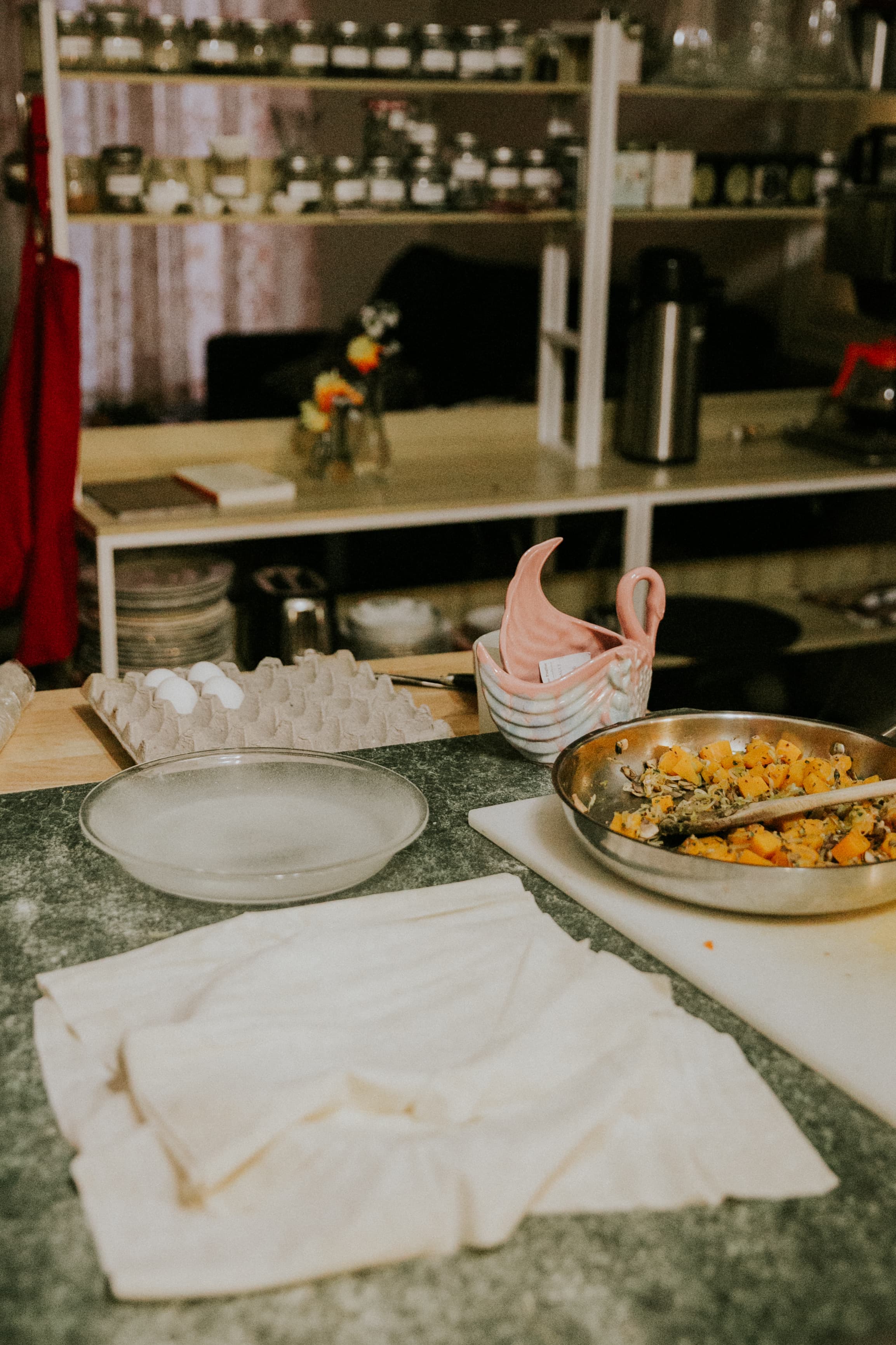 A kitchen countertop with a bowl of mixed ingredients, an empty plate, egg carton, and a stack of cloths.