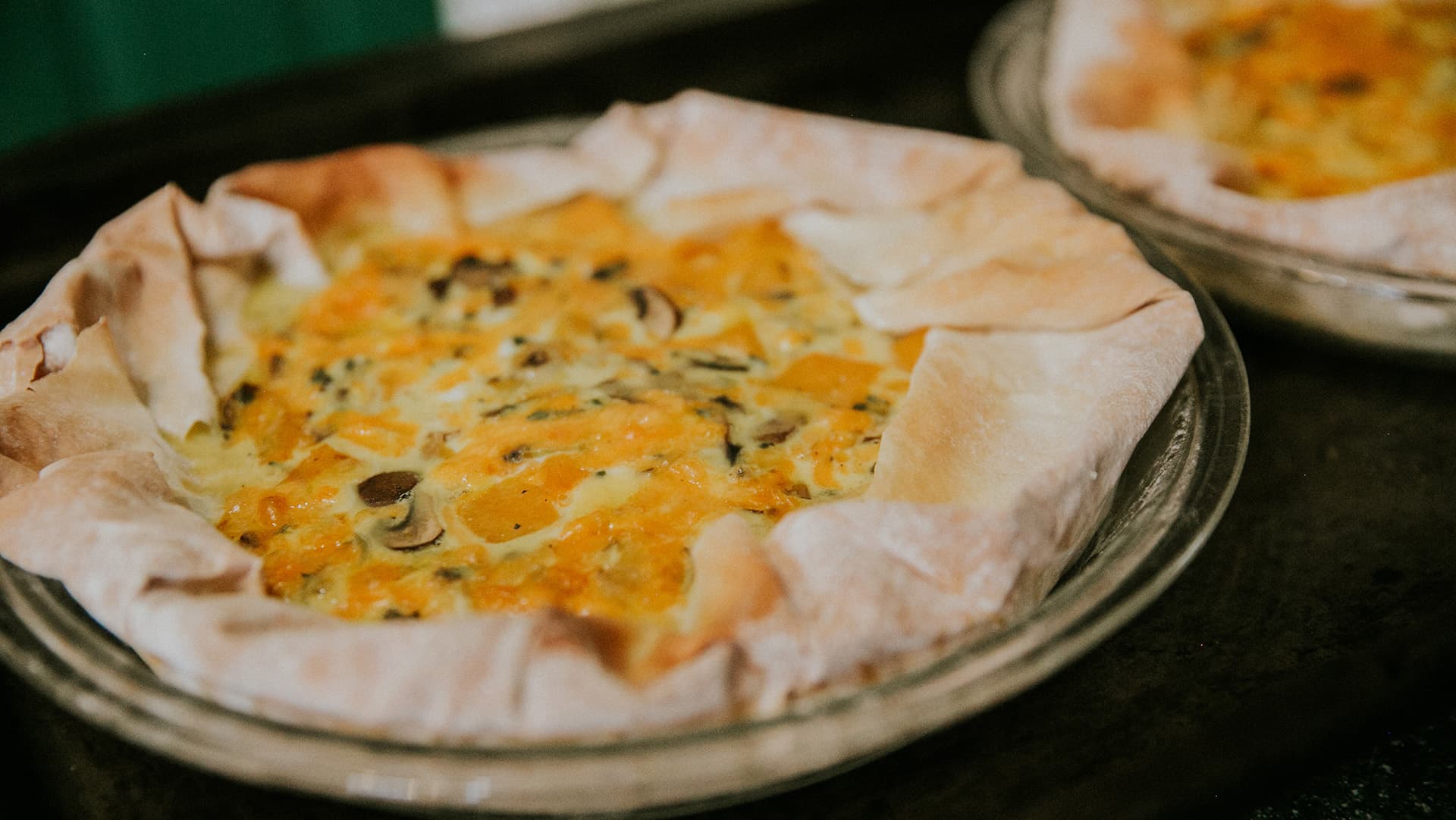 Two savory pies with flaky crusts filled with vegetables and cheese.