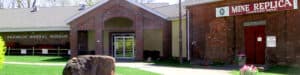 Entrance to Franklin Mineral Museum with Mine Replica display, featuring red brick architecture and large mineral specimen on lawn