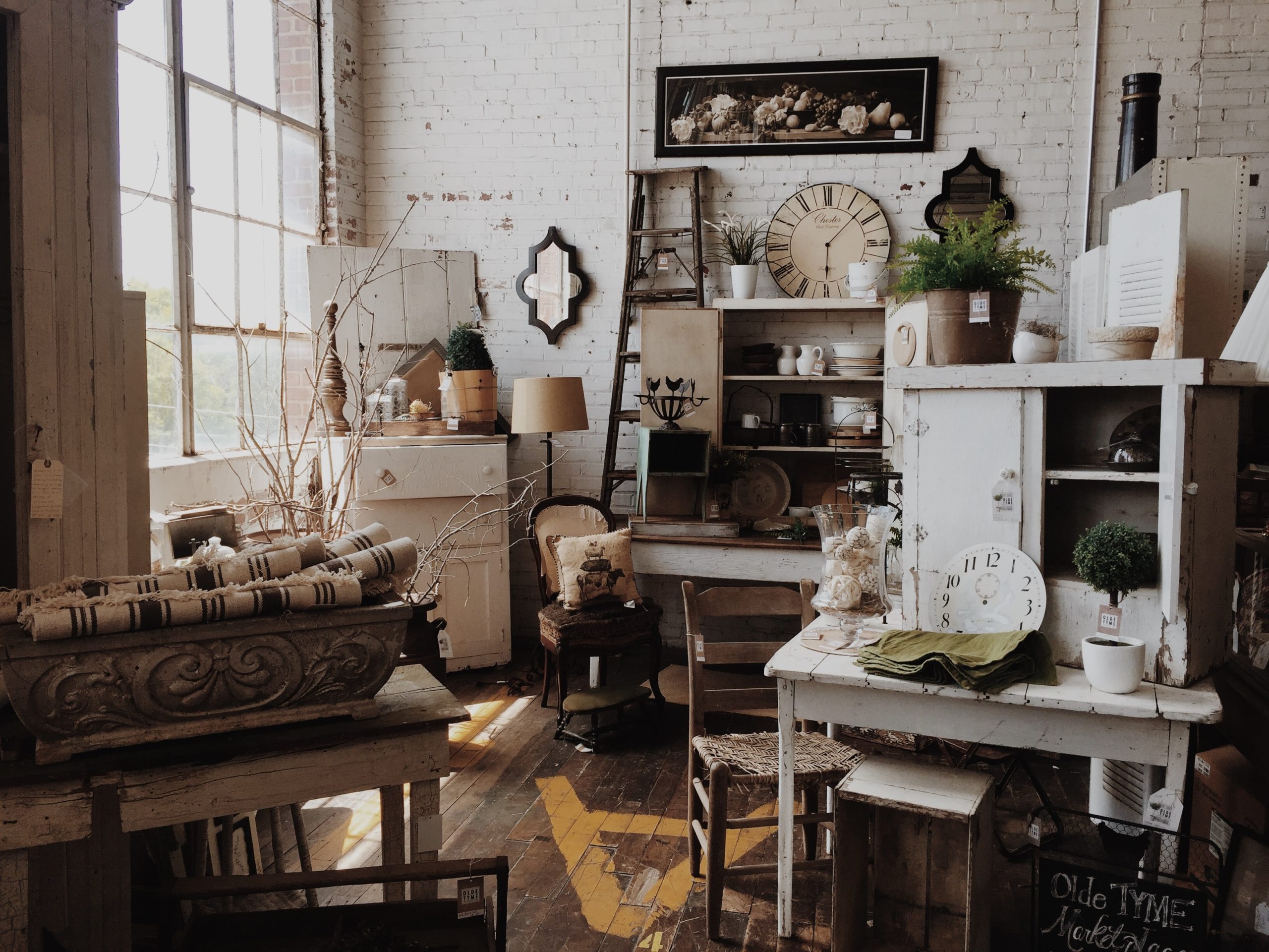 A naturally-lit room filled with neutral-toned antiques and home decor.