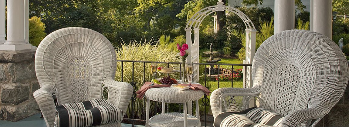 Two white wicker chairs with black and white cushions; white wicker table with objects on it