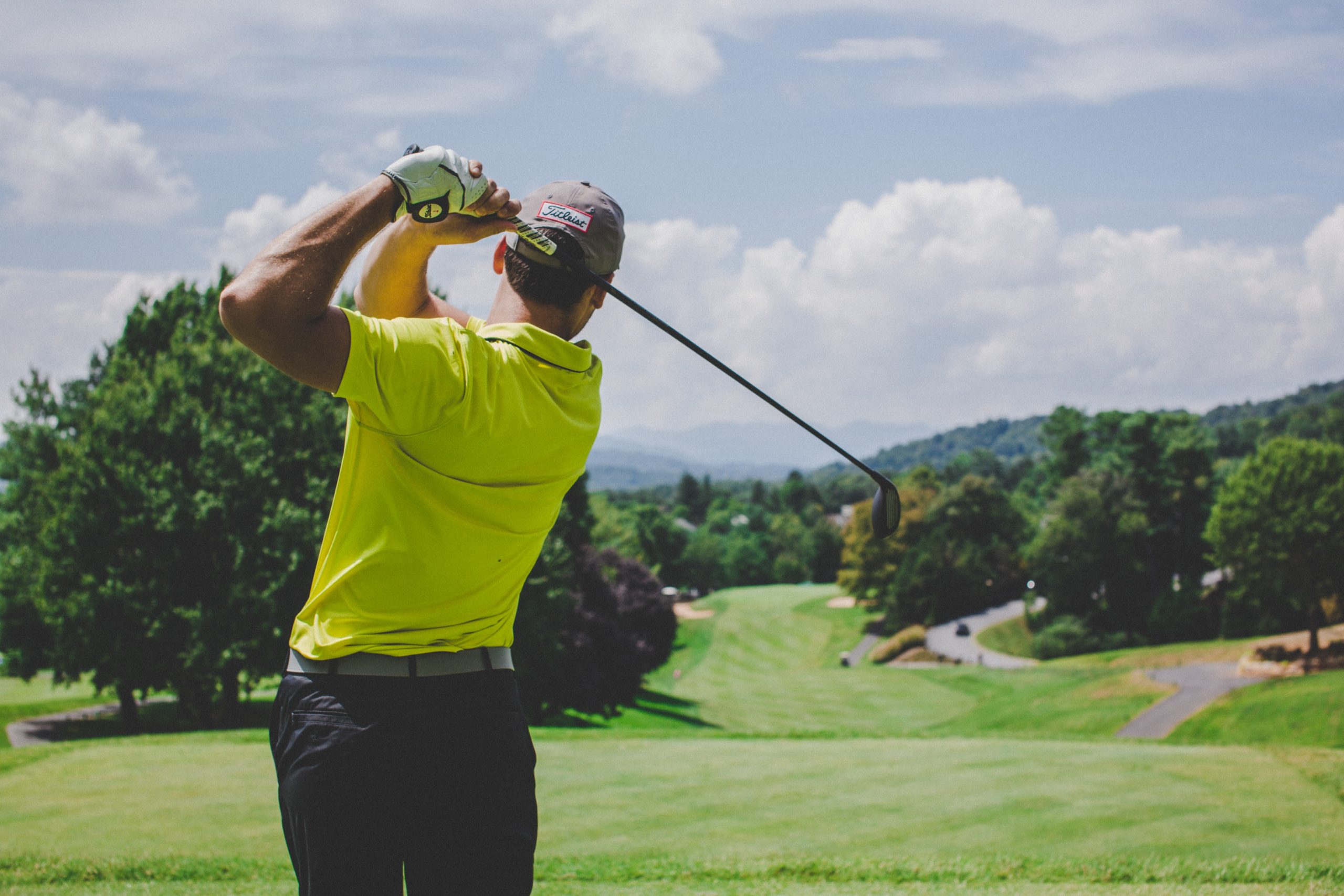 A man swinging a golf club under blue skies.