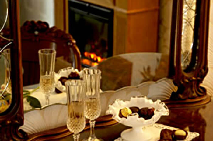 Two champagne flutes and white milk glass dish with candy reflected in the mirror