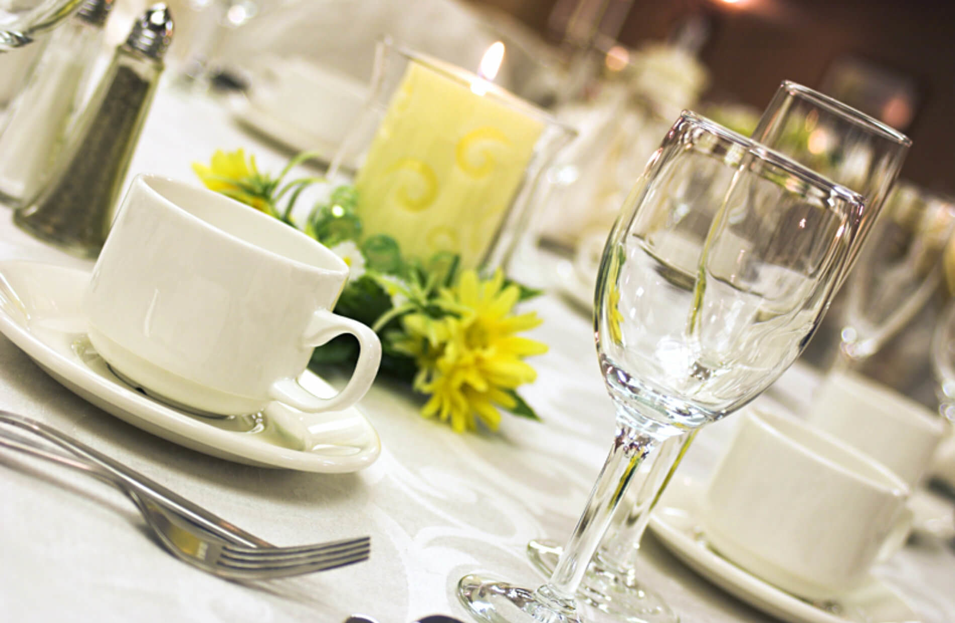 Table set with white cloth. white dishes, wine glasses and candle