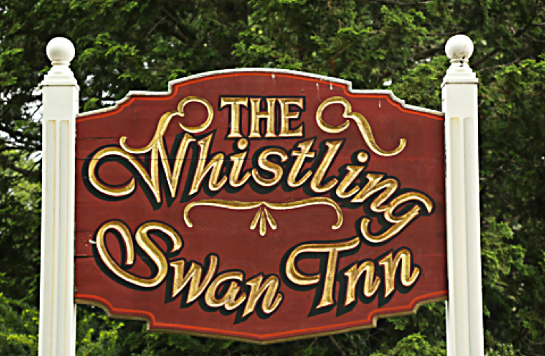 Large Exterior red sign with gold words: The Whistling Swan Inn