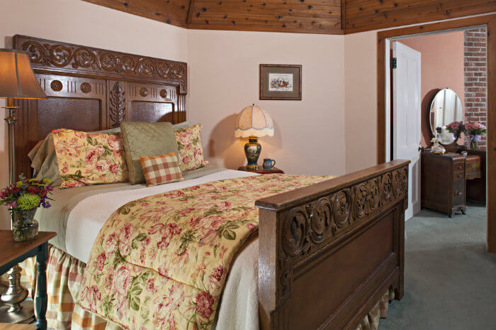 Large wooden bed with cream and pink bedding