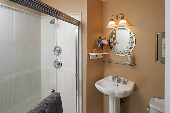 White tile shower in peach walled bathroom with white vanity