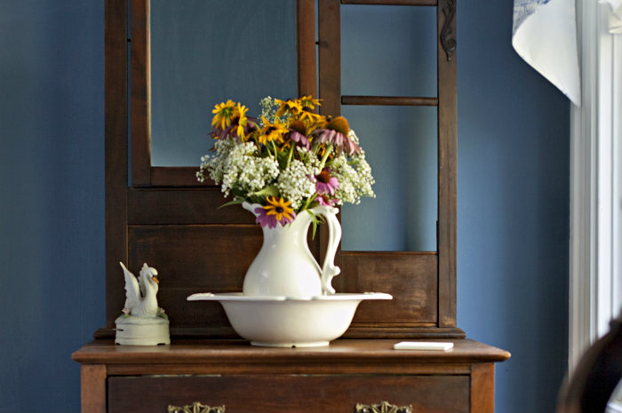 Antique wooden bureau with white ewer and basin full of flowers