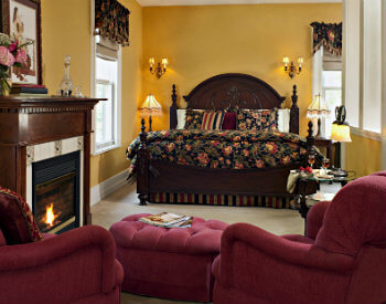 king bed with black floral bedding, gold walls and 2 chairs