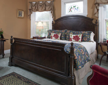 king bed with soft white linens and blue floral comforter; gold walls