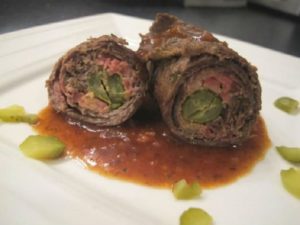 German dish of rolled beef with pickles on a white plate