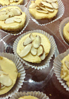 Mini cheesecakes in white paper cups with almonds on top