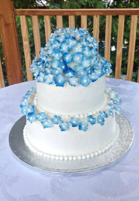 White two-story cake with blue violets on silver platter