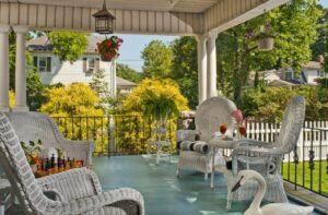A photograph of the veranda at the Whistling Swan Inn. A chess board is set up on a small table to the left. On the right hand side of the image, a pair of refreshing iced teas are standing side by side