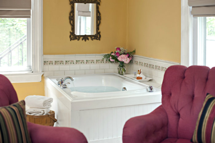 Large soaking tub facing two red wingback chairs