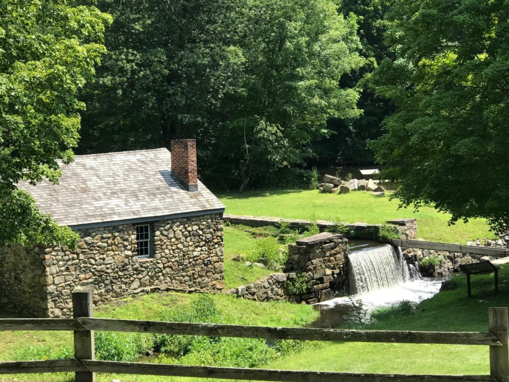 Old stone building with small waterfall into Morris Canal at Waterloo Village Historic Site.